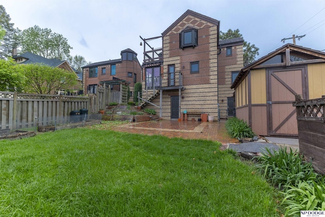 rear view of property featuring an outbuilding, fence, a storage unit, a yard, and a patio
