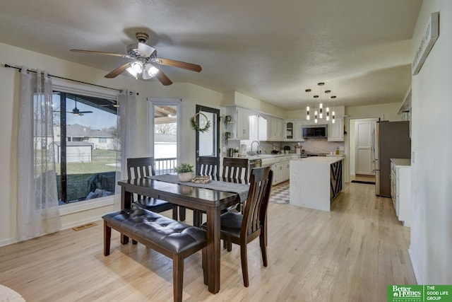 dining area featuring light wood-type flooring, visible vents, and ceiling fan