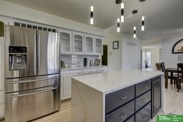 kitchen featuring glass insert cabinets, white cabinetry, stainless steel refrigerator with ice dispenser, and light wood-style floors