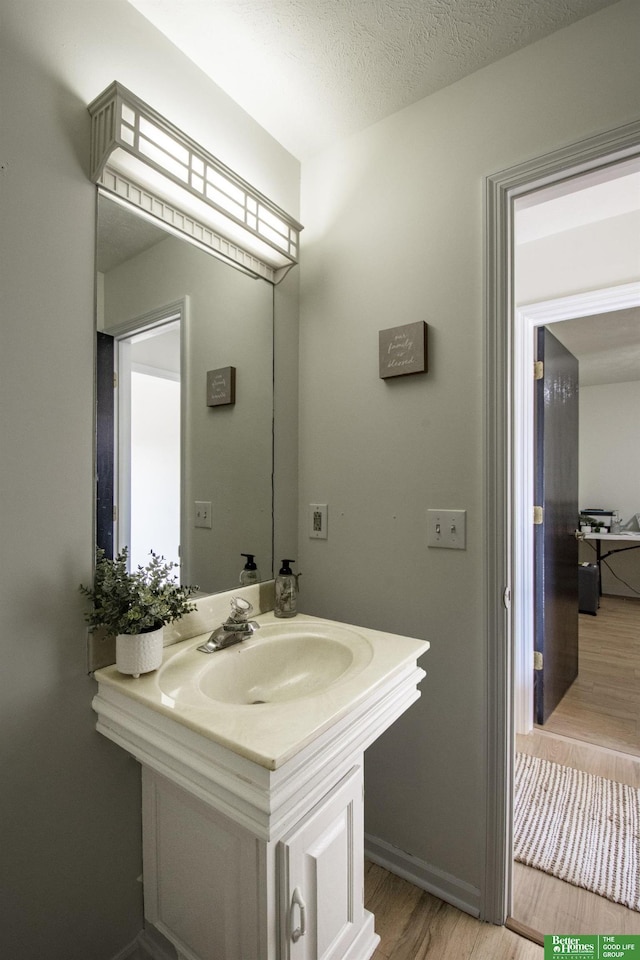bathroom featuring baseboards, wood finished floors, vanity, and a textured ceiling