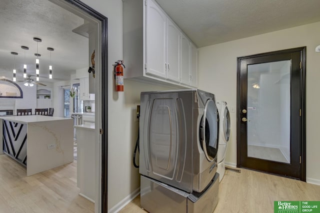 laundry room with cabinet space, a textured ceiling, independent washer and dryer, and light wood-type flooring