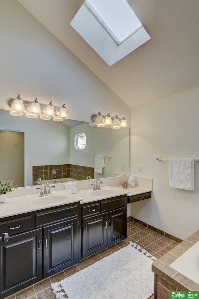 full bathroom with lofted ceiling with skylight, a sink, double vanity, and tiled tub