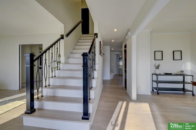 staircase with baseboards, wood finished floors, and recessed lighting