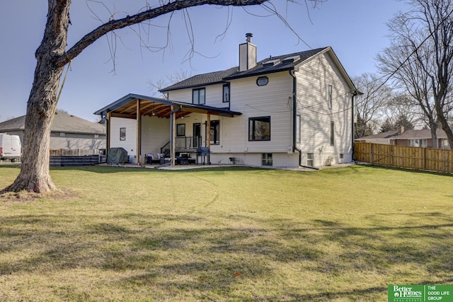rear view of property with a patio, a chimney, fence, and a yard