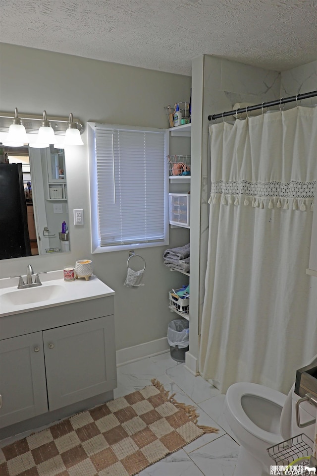 full bath with marble finish floor, vanity, toilet, and a textured ceiling