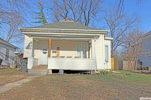view of front of house with a front lawn, a chimney, a shingled roof, and covered porch