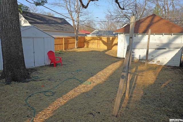 view of yard with a fenced backyard, an outbuilding, and a storage shed