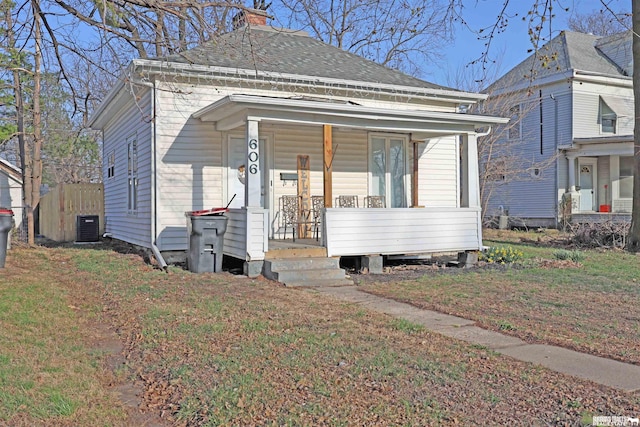 view of front facade with a chimney, central AC, a porch, and a front yard