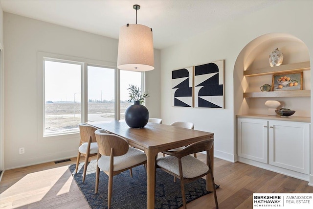 dining room featuring baseboards, plenty of natural light, light wood-type flooring, and visible vents