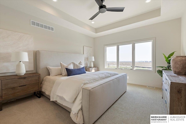 bedroom featuring light colored carpet, visible vents, recessed lighting, and a raised ceiling