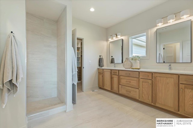 full bathroom featuring double vanity, a sink, a spacious closet, recessed lighting, and tiled shower