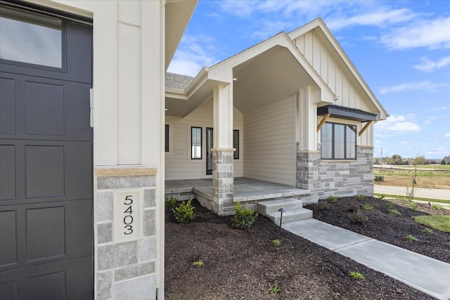property entrance with a shingled roof, board and batten siding, and stone siding