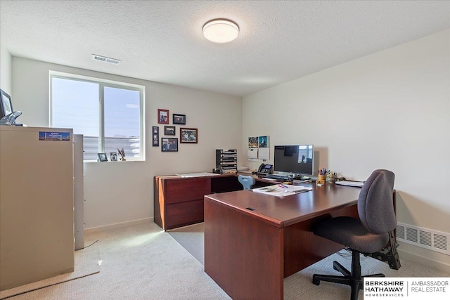 office area featuring baseboards, light carpet, a textured ceiling, and visible vents