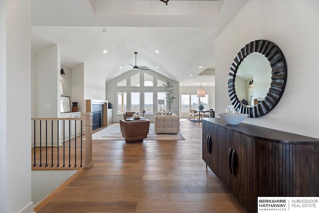 living room featuring a glass covered fireplace, ceiling fan, recessed lighting, hardwood / wood-style flooring, and vaulted ceiling