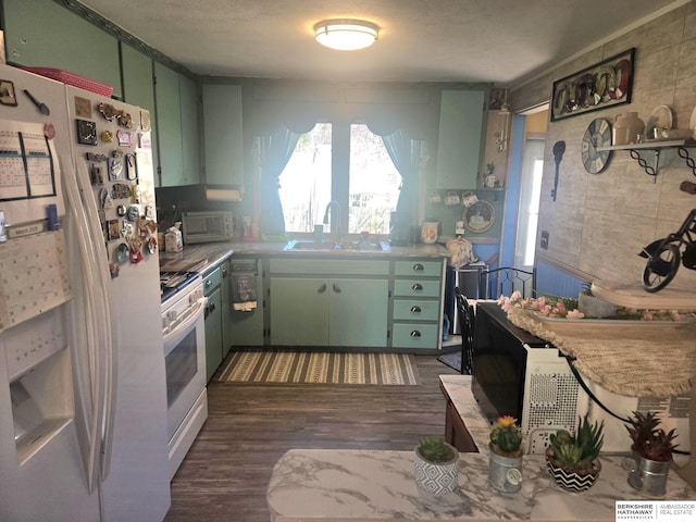 kitchen with green cabinets, white appliances, and a sink