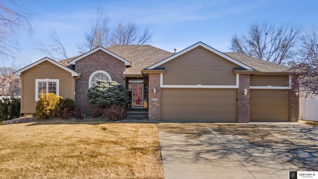 ranch-style house with concrete driveway, an attached garage, a front lawn, brick siding, and a shingled roof