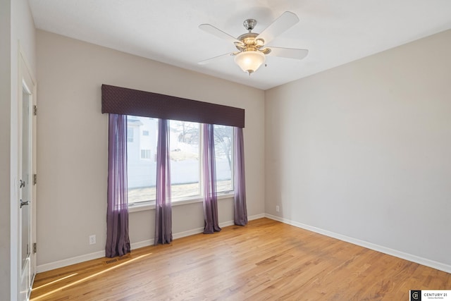 empty room featuring baseboards, visible vents, light wood-style floors, and a ceiling fan