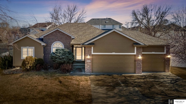 view of front of home with a front yard, concrete driveway, an attached garage, brick siding, and a shingled roof