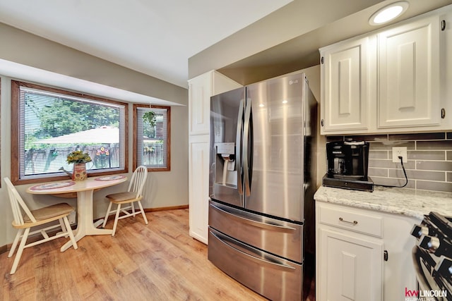 kitchen with appliances with stainless steel finishes, baseboards, light wood-type flooring, backsplash, and white cabinets