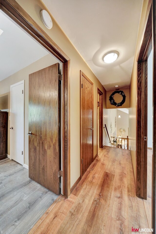 corridor featuring an upstairs landing and light wood-style floors