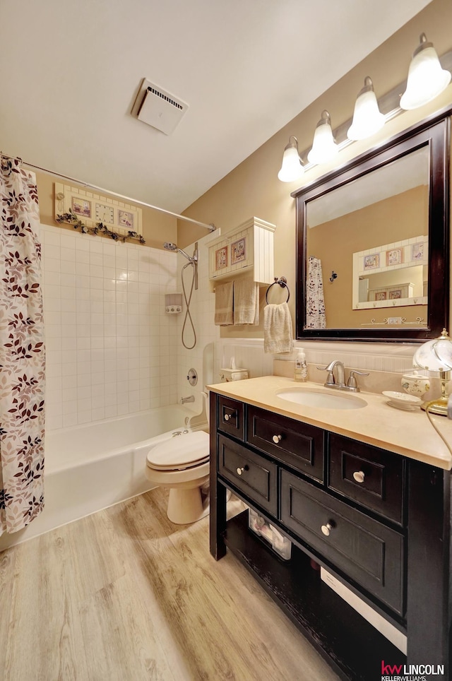 bathroom with wood finished floors, toilet, shower / bath combo with shower curtain, and vanity