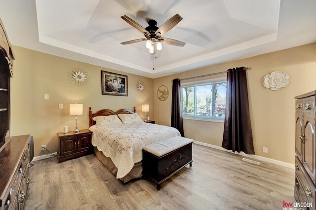 bedroom featuring a tray ceiling and light wood finished floors