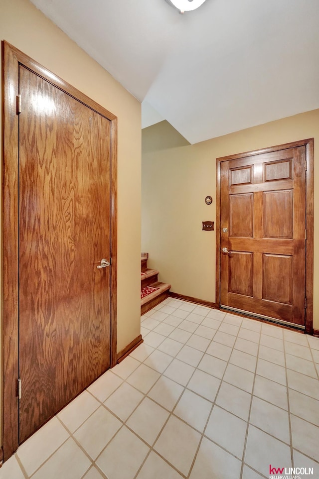 entrance foyer with stairway, light tile patterned floors, and baseboards