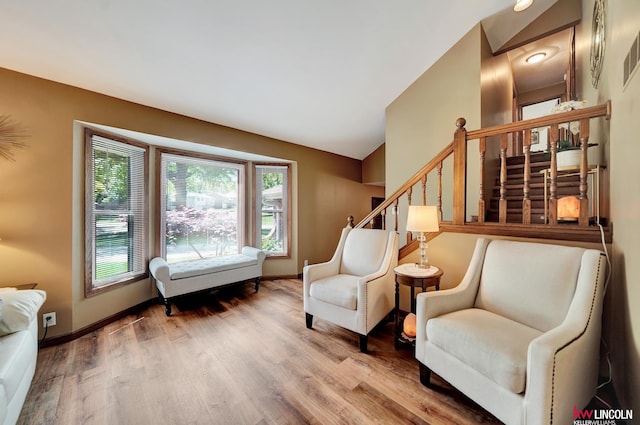 sitting room with wood finished floors, stairs, baseboards, and lofted ceiling