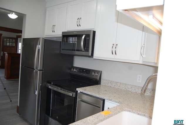 405 E 5th St, Mccook, NE 69001 - kitchen with light stone countertops, light wood-style flooring, white cabinets, appliances with stainless steel finishes, and a sink