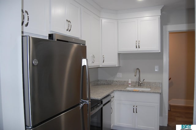 405 E 5th St, Mccook, NE 69001 - kitchen with light stone counters, white cabinets, appliances with stainless steel finishes, a sink, and wood finished floors