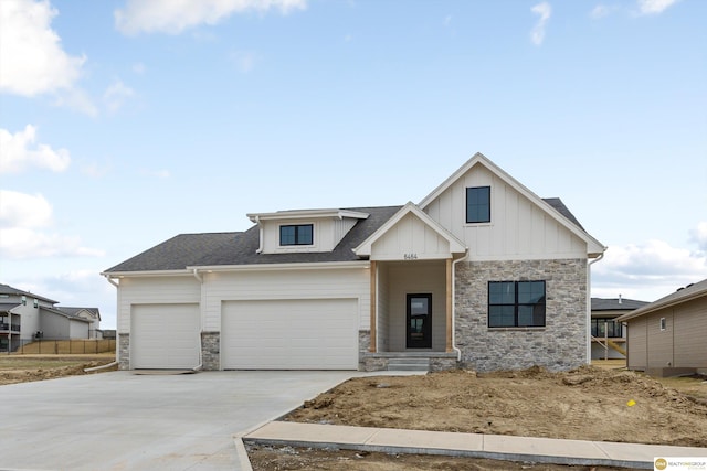 modern farmhouse style home with concrete driveway, stone siding, board and batten siding, a garage, and a shingled roof