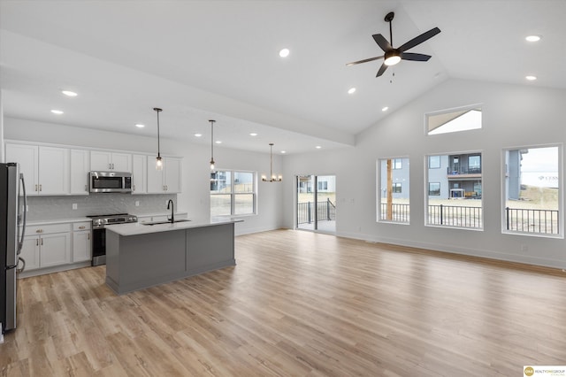 kitchen with tasteful backsplash, appliances with stainless steel finishes, a sink, ceiling fan with notable chandelier, and open floor plan