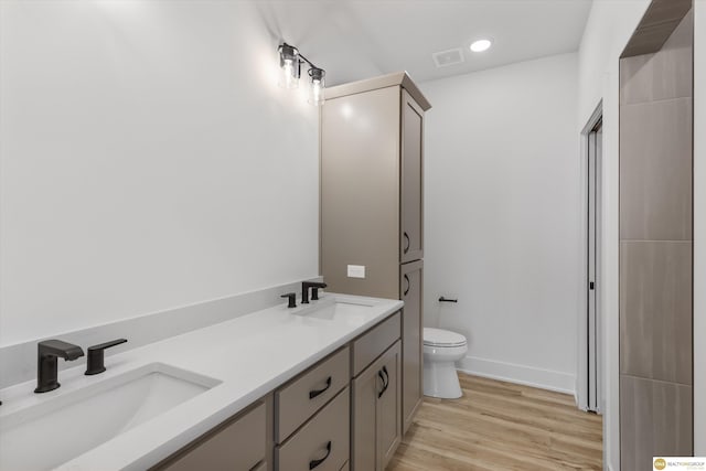 bathroom with visible vents, a sink, toilet, and wood finished floors