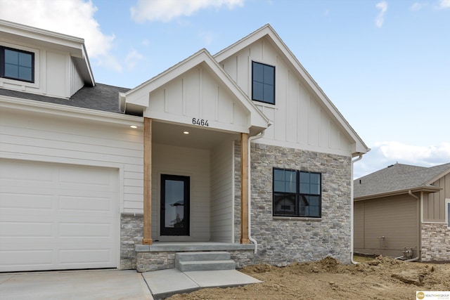 view of front of house featuring stone siding, board and batten siding, driveway, and a garage