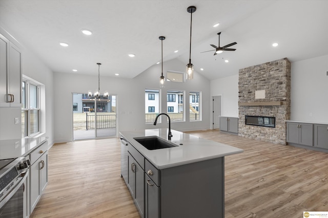 kitchen with gray cabinets, a sink, open floor plan, stainless steel appliances, and ceiling fan with notable chandelier