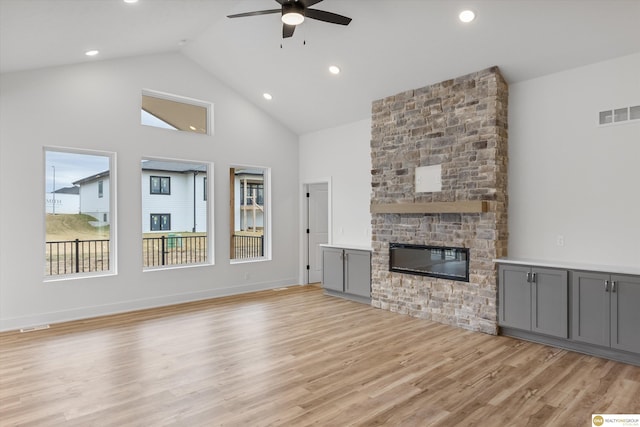 unfurnished living room with light wood-type flooring, high vaulted ceiling, ceiling fan, visible vents, and a fireplace