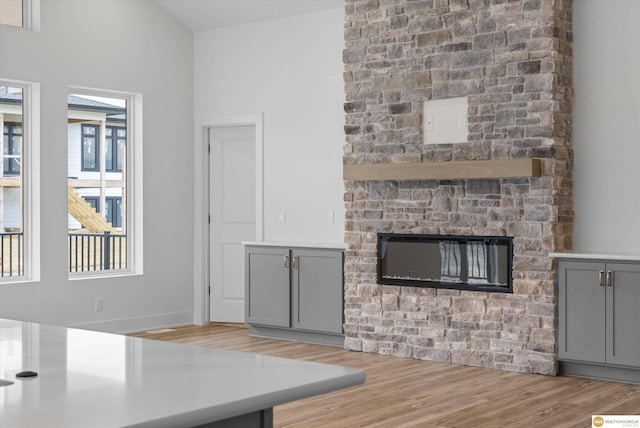 unfurnished living room with wood finished floors and a stone fireplace