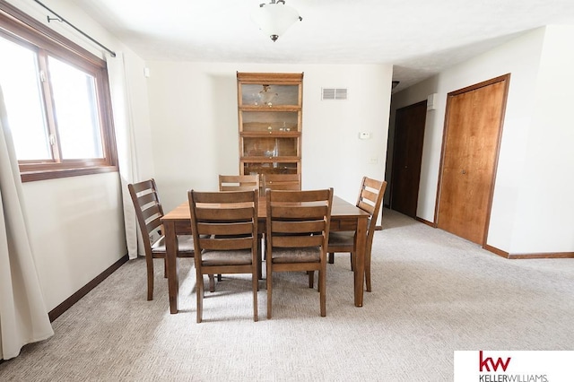 dining area featuring light carpet, visible vents, and baseboards