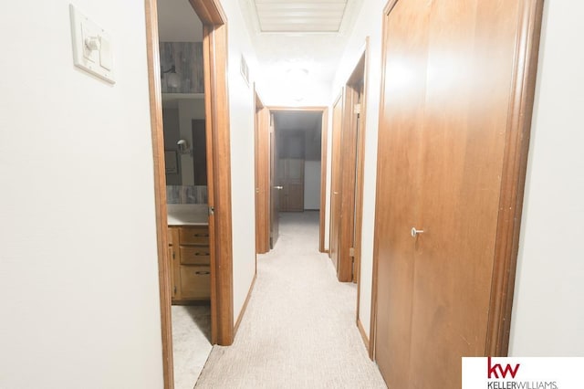 hallway featuring light colored carpet and visible vents