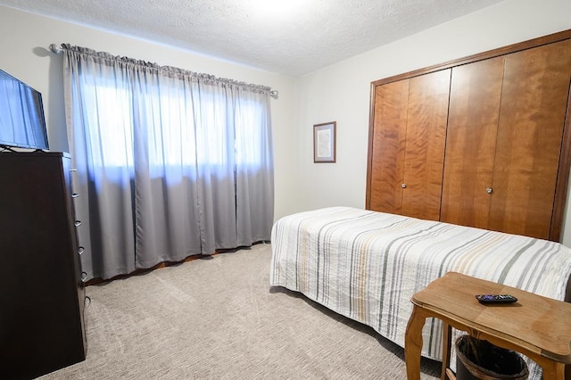 bedroom featuring a closet, light colored carpet, and a textured ceiling