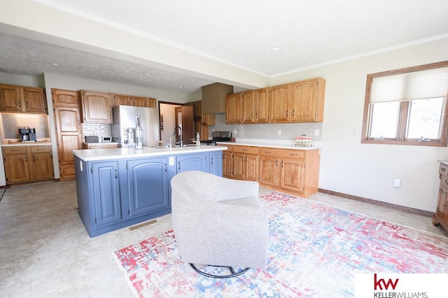 kitchen with tasteful backsplash, appliances with stainless steel finishes, light countertops, a sink, and a center island with sink