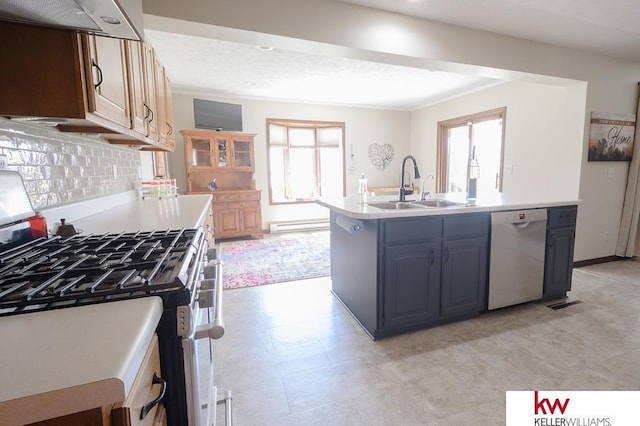 kitchen with a sink, light countertops, appliances with stainless steel finishes, an island with sink, and baseboard heating