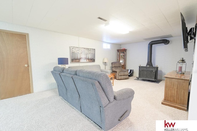 living area featuring a wood stove, carpet flooring, and visible vents