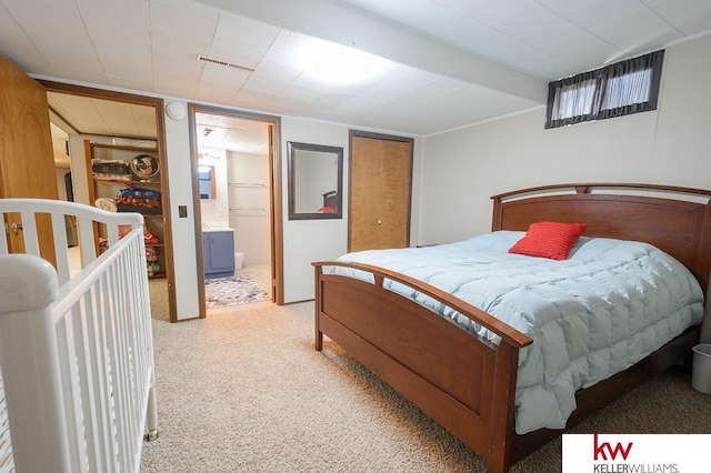 bedroom featuring light carpet, visible vents, and connected bathroom