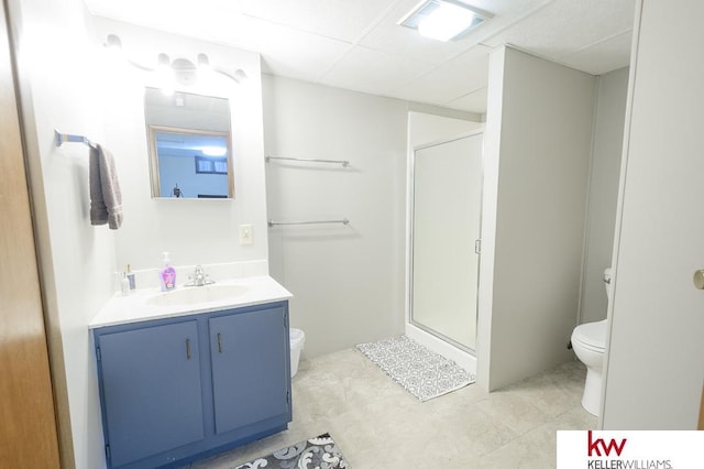 bathroom with vanity, a stall shower, a paneled ceiling, and toilet