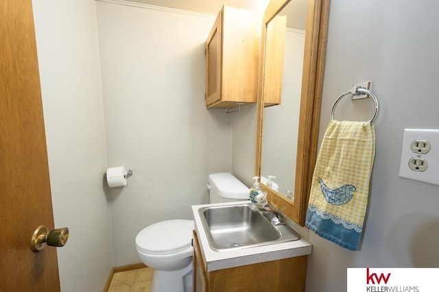 bathroom with toilet, vanity, and baseboards