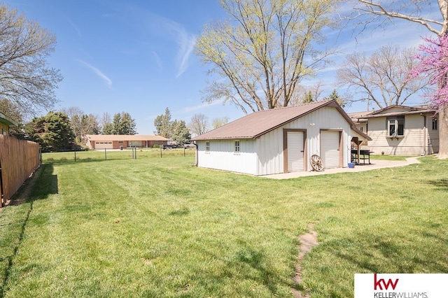 view of yard with an outbuilding, a detached garage, and fence