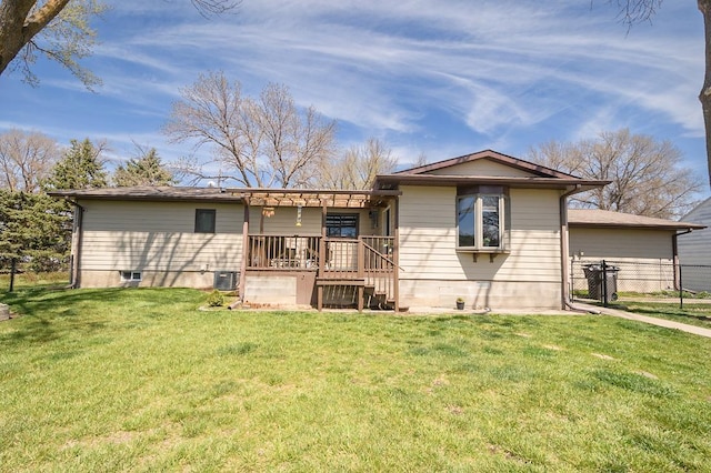 rear view of property featuring fence, cooling unit, and a lawn