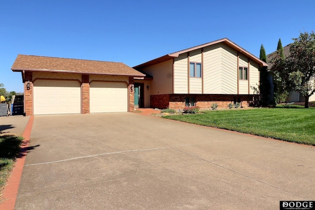 split level home with a front yard, an attached garage, brick siding, and concrete driveway