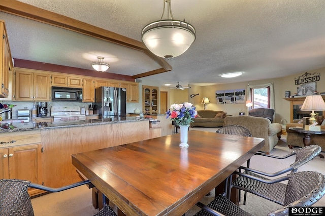 dining area with a ceiling fan, beamed ceiling, and a textured ceiling